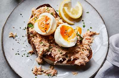 Crab and soft boiled eggs on toast with lemon wedge on the side