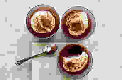 Photo looking down on three irish cream and chocolate mousse pot desserts with a spoonful taken out of one of them and the spoon set next to one of the desserts