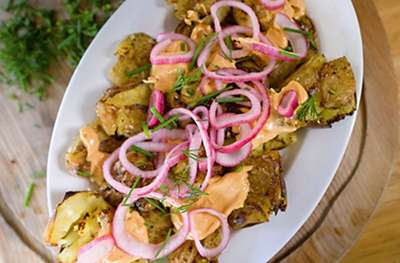 A plate of crispy smashed potatoes and red pickled onion