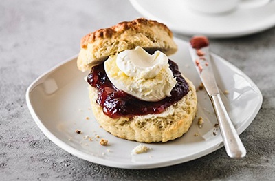Image of scone covered with jam & cream