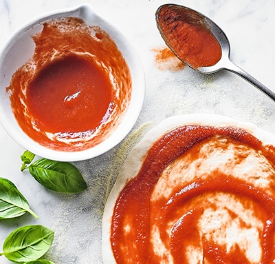 Image of tomato sauce on pizza base