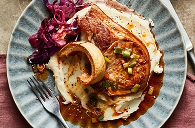 Pork chops with crackling, cider-braised red cabbage & salad onion butter